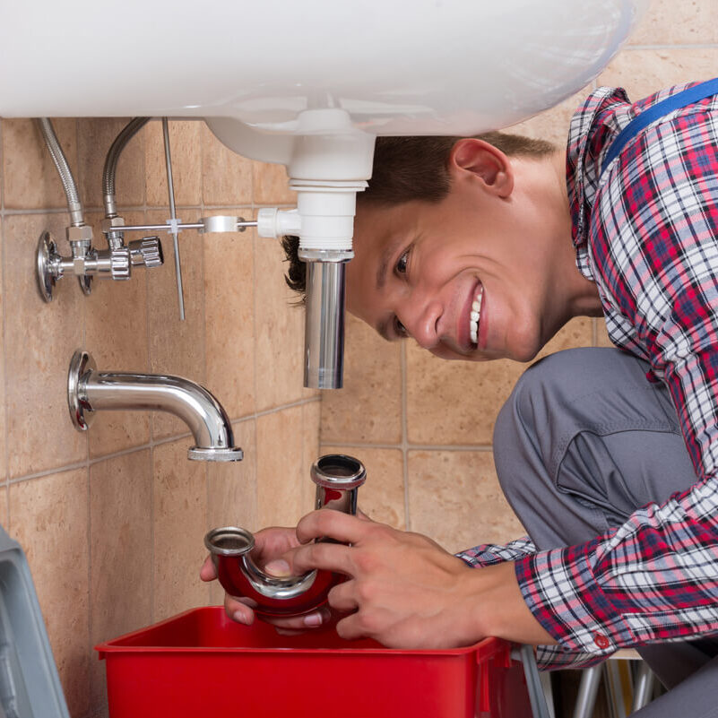 Plumber Installing Sink Pipe in Bathroom